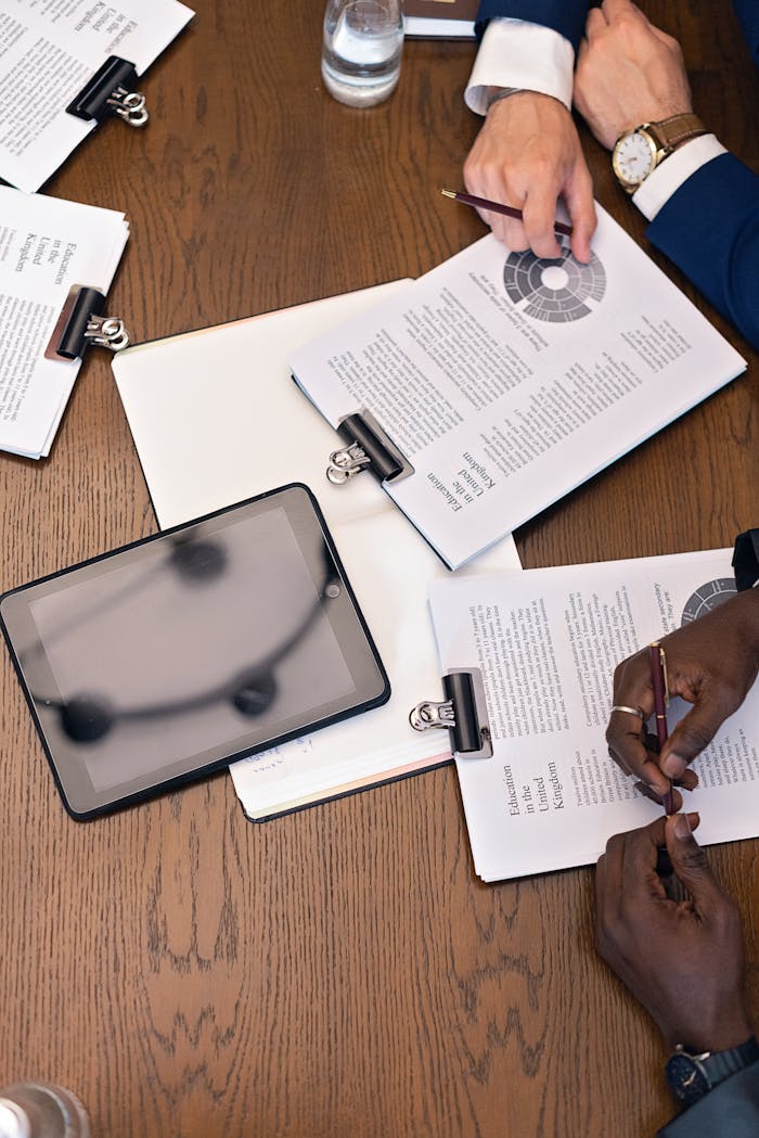 home-services-01 Top view of a business meeting with hands, tablets, and documents on a table.